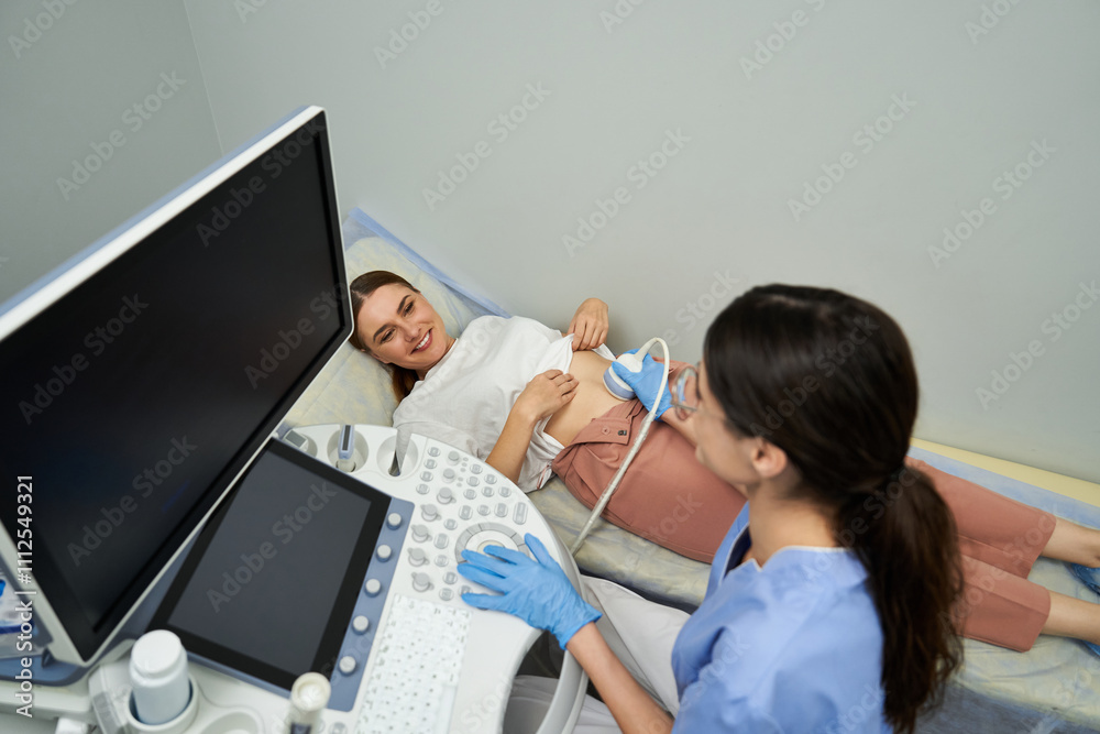 Fototapeta premium A gynecologist performs a detailed ultrasound on a relaxed woman at a modern clinic.