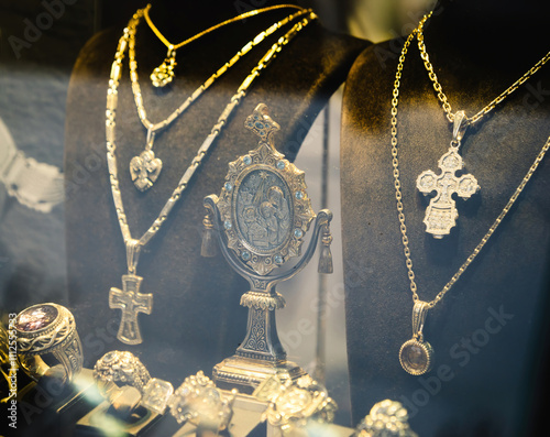 Jewelry storefront display featuring ornate gold necklaces, crosses, and rings with intricate detailing, symbolizing elegance and fine craftsmanship photo