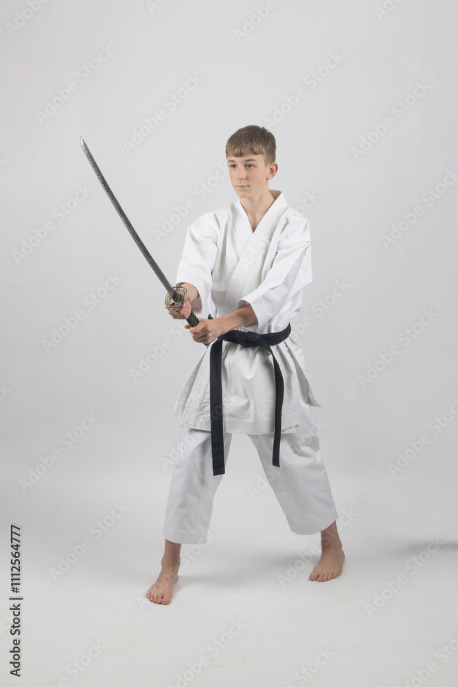 Fifteen year old male teenage karate black belt using a katana, studio shot against a white background Fifteen year old male teenage karate black belt using a katana, studio shot against a white background