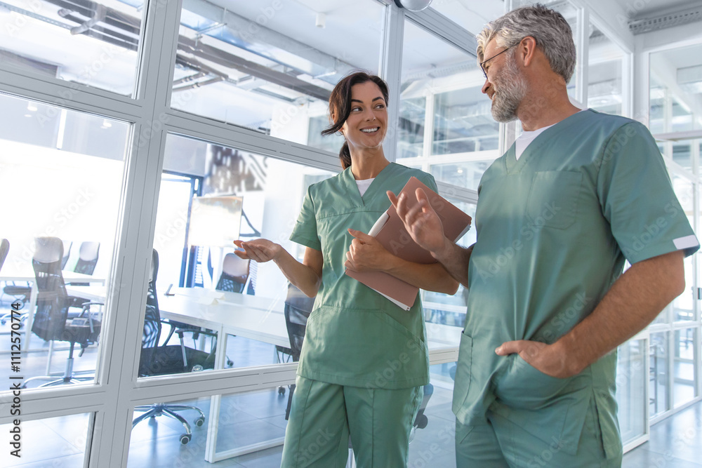 Two doctors walking in the clinic corridor and talking Two doctors walking in the clinic corridor and talking