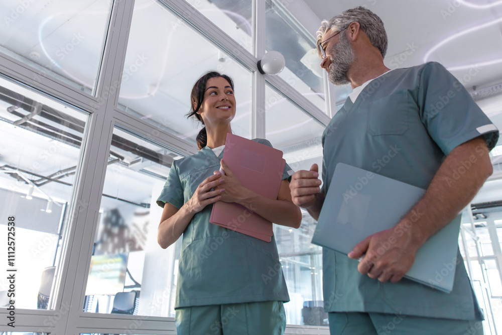 Two doctors walking in the clinic corridor and talking Two doctors walking in the clinic corridor and talking