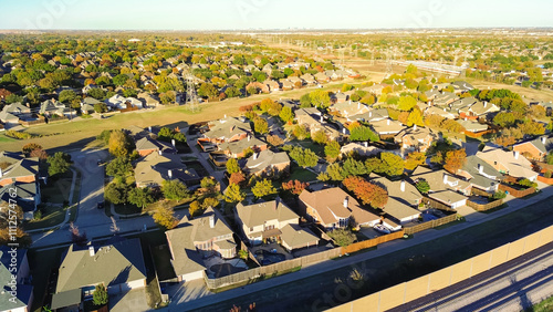 Upscale residential area with downtown Dallas in distance background, power pylons and precast concrete walls noise barriers, sound mitigation light railroad Belt Line Road in Coppell, TX, aerial photo