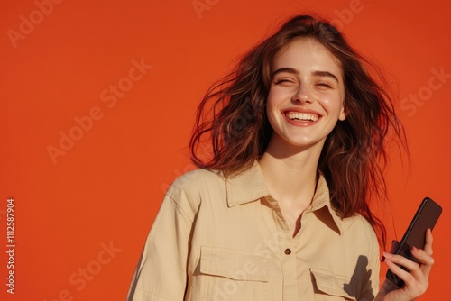 A woman smiles while holding her cell phone, possibly enjoying a conversation or browsing the internet