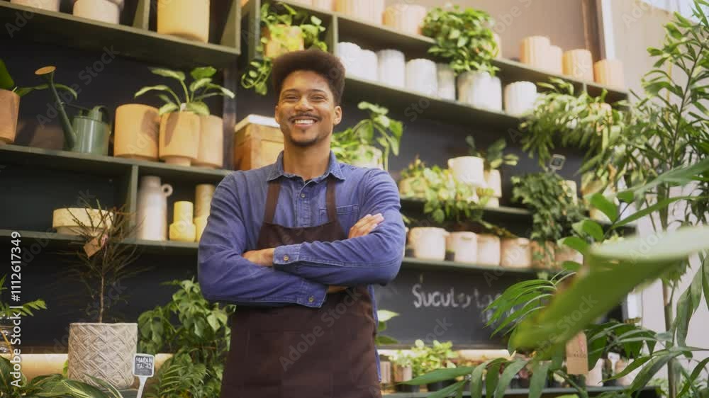 Confident plant shop employee in apron smiling with arms crossed, surrounded by vibrant greenery. Young store manager enjoying his job in a cozy, nature-inspired retail environment. Confident plant shop employee in apron smiling with arms crossed, surrounded by vibrant greenery. Young store manager enjoying his job in a cozy, nature-inspired retail environment.