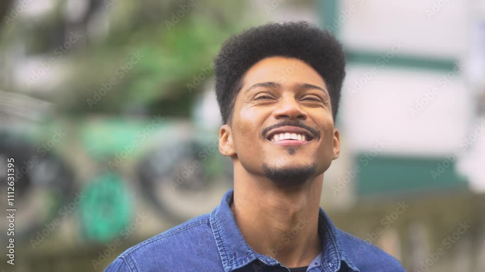 Smiling African American man admiring his surroundings as the camera moves around him. Joyful and relaxed, he enjoys the peaceful outdoor environment in a casual denim shirt. Smiling African American man admiring his surroundings as the camera moves around him. Joyful and relaxed, he enjoys the peaceful outdoor environment in a casual denim shirt.