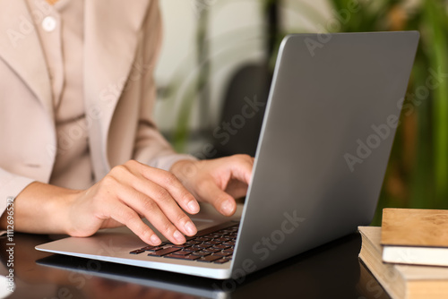 Female author using laptop at table in cafe, closeup