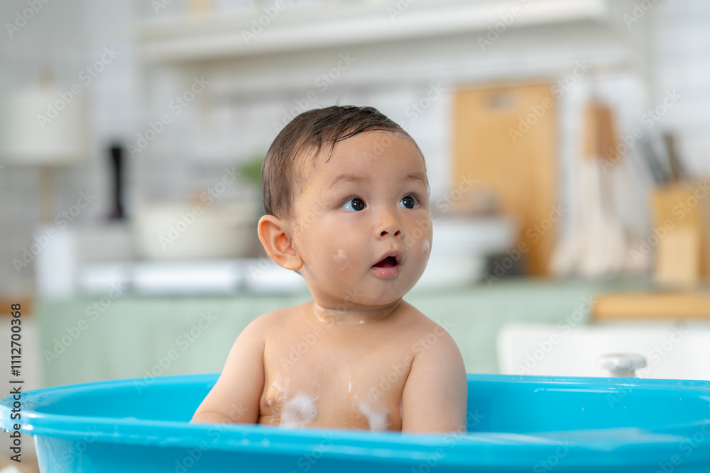 Asian baby taking a bath in a blue tub at home. Asian baby taking a bath in a blue tub at home.
