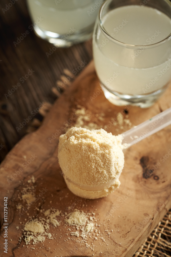 Fototapeta premium Whey protein powder in a scoop with fresh natural whey on a table