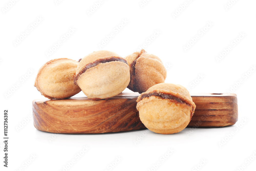 Wooden board of sweet walnut shaped cookies with boiled condensed milk on white background Wooden board of sweet walnut shaped cookies with boiled condensed milk on white background