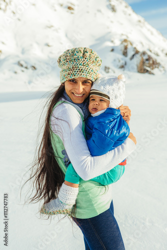 A beautiful Indian (Asian) mother and her one-year-old son pose in winter clothes in fresh snowfall on top of Fox Glacier in Weheka, South Island of New Zealand.  photo