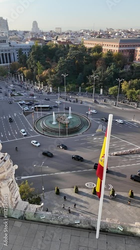 View of Palacio de Cibeles in Madrid on a sunny day, featuring historic architecture, traffic, and a vibrant urban setting.
