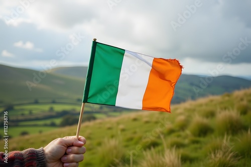 Hand holding irish flag in scenic countryside landscape