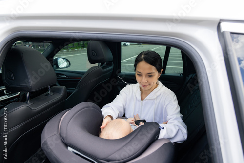 Mother securing baby in car seat safely