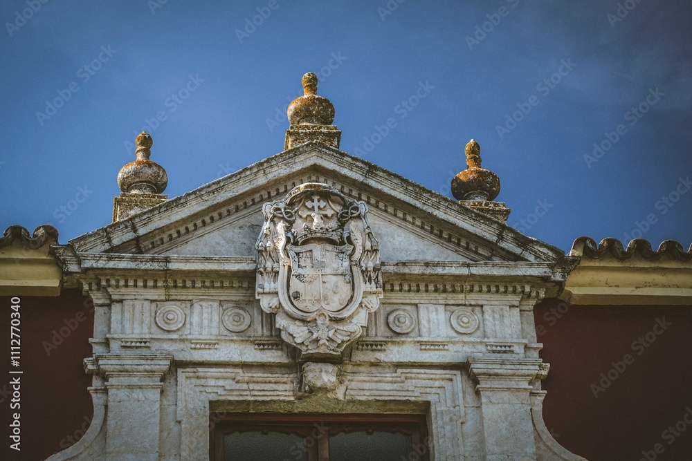 Close-up of an ornate stone facade with a coat of arms under a clear blue sky in Andalusia, Spain Close-up of an ornate stone facade with a coat of arms under a clear blue sky in Andalusia, Spain