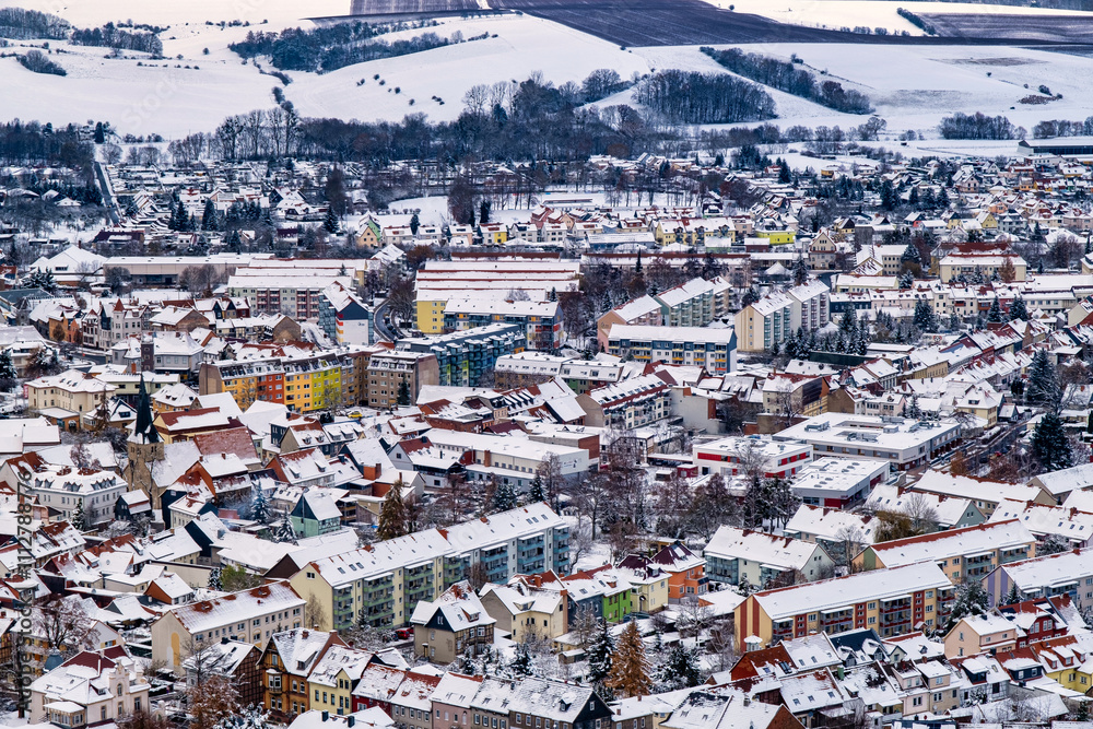 A snowy landscape with a town in the distance. The sky is cloudy and the snow is covering the ground. Germany.