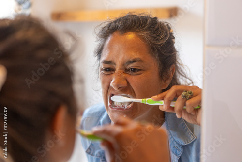 Woman Brushing Teeth with Determination in Bathroom Mirror