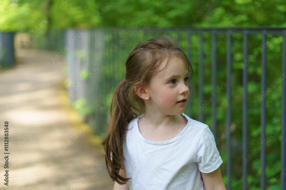 Beautiful cheerful girl in a white T-shirt having fun in the summer outdoors. Concept of an active, mobile, sincere child Beautiful cheerful girl in a white T-shirt having fun in the summer outdoors. Concept of an active, mobile, sincere child