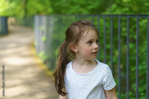 Beautiful cheerful girl in a white T-shirt having fun in the summer outdoors. Concept of an active, mobile, sincere child