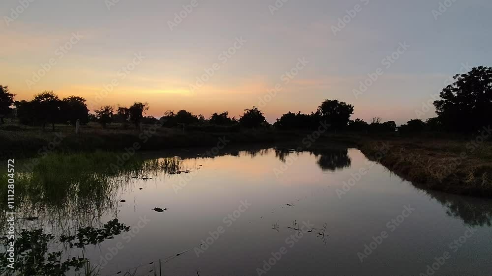 A beautiful sunset painted the sky orange and reflected on a tranquil lake surrounded by lush green trees. A beautiful sunset painted the sky orange and reflected on a tranquil lake surrounded by lush green trees.