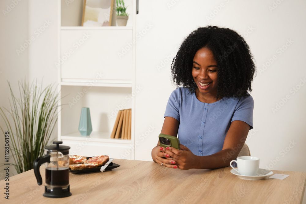 African American woman enjoying coffee and smartphone at home African American woman enjoying coffee and smartphone at home