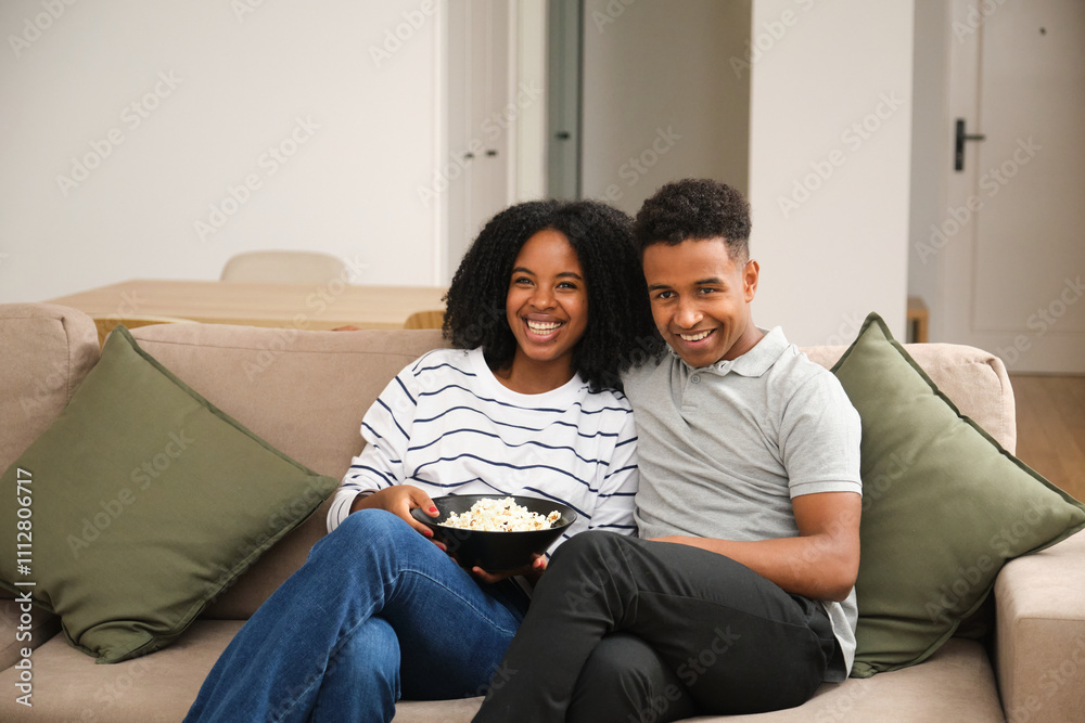 Young couple relaxing on the couch at home with popcorn Young couple relaxing on the couch at home with popcorn