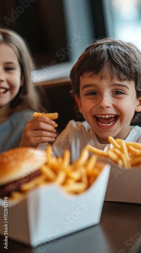 Two joyful children enjoying burgers and fries at a casual dining spot during...
