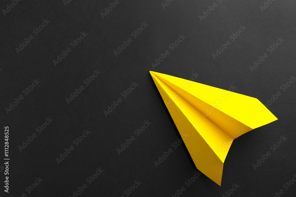 One handmade yellow paper plane on black background, top view. Space for text One handmade yellow paper plane on black background, top view. Space for text