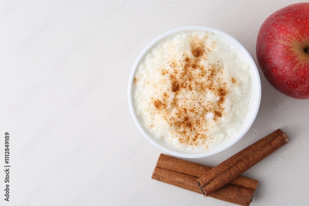 Delicious rice pudding with apple and cinnamon on light background, flat lay. Space for text Delicious rice pudding with apple and cinnamon on light background, flat lay. Space for text