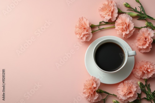 Coffee cup surrounded by pink flowers on a soft pink background during the mo...