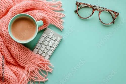 Cozy workspace setup with coffee, scarf, and keyboard on mint green background
