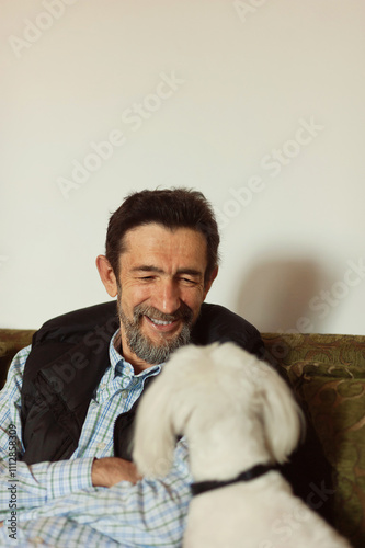 An older man is having fun with his best friend - maltese dog