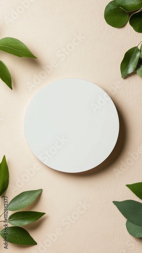 Circle on a cream surface surrounded by green leaves creates a serene atmosph...