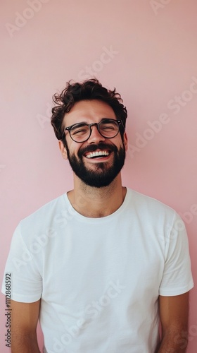 Smiling man poses confidently against a pink background wearing a simple whit...