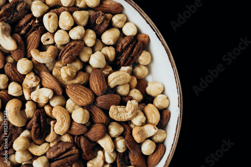 Delicious assortment of mixed nuts in a bowl on dark background