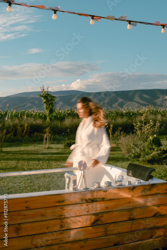 A woman in a white robe enters a hot tub in the mountains photo