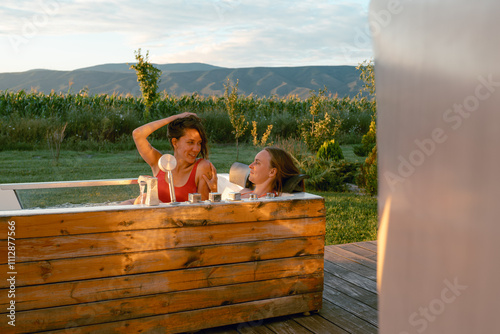 Two women relax in a hot tub with a scenic view photo