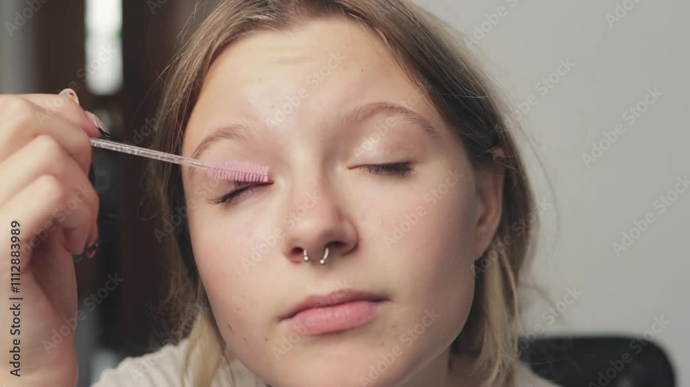 Young woman carefully enhancing her eyebrows with a small brush, focusing on shape and definition while showcasing her beauty routine in a cozy indoor setting Young woman carefully enhancing her eyebrows with a small brush, focusing on shape and definition while showcasing her beauty routine in a cozy indoor setting