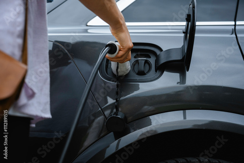 A woman connects charging to an electric car photo