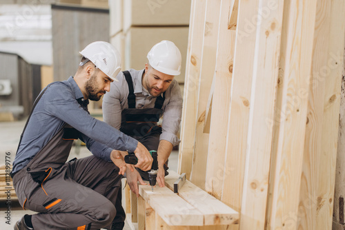 Carpenters building wooden structure using cordless screwdriver in workshop