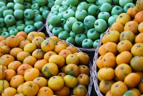 food fruits background of pile of juicy, bright green colored apples and ripe orange mandarin, tangerine in wicker basket. Autumn crop harvest. Fall season. Gandagana rural tourism festival in Batumi