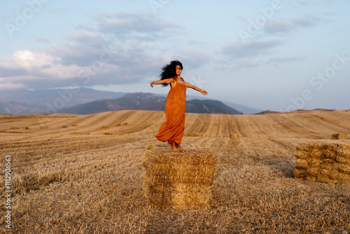 Carefree female spinning on hayrick in field