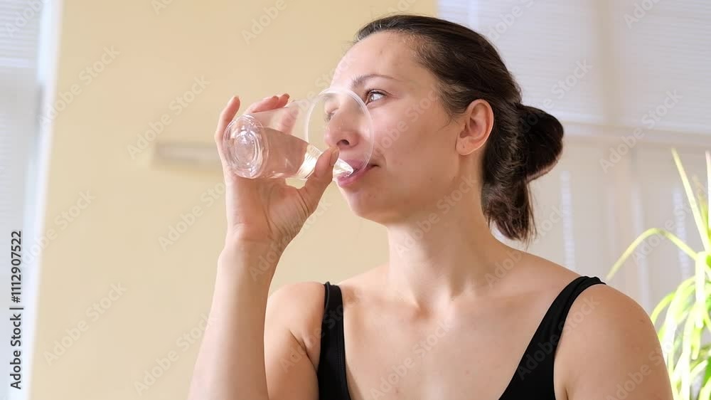 Young caucasian woman is drinking water after yoga practices. Happy morning, wellness at home. Yoga trainer and instructor is resting. Young caucasian woman is drinking water after yoga practices. Happy morning, wellness at home. Yoga trainer and instructor is resting.