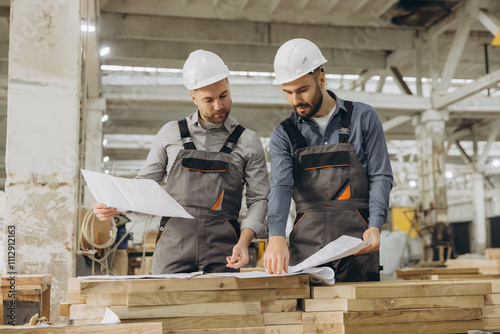 Engineers examining blueprints for modular building project in factory