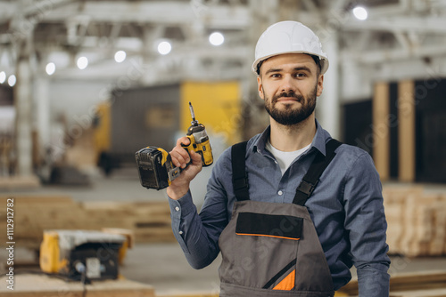Photos Construction worker holding cordless drill in modular building factory