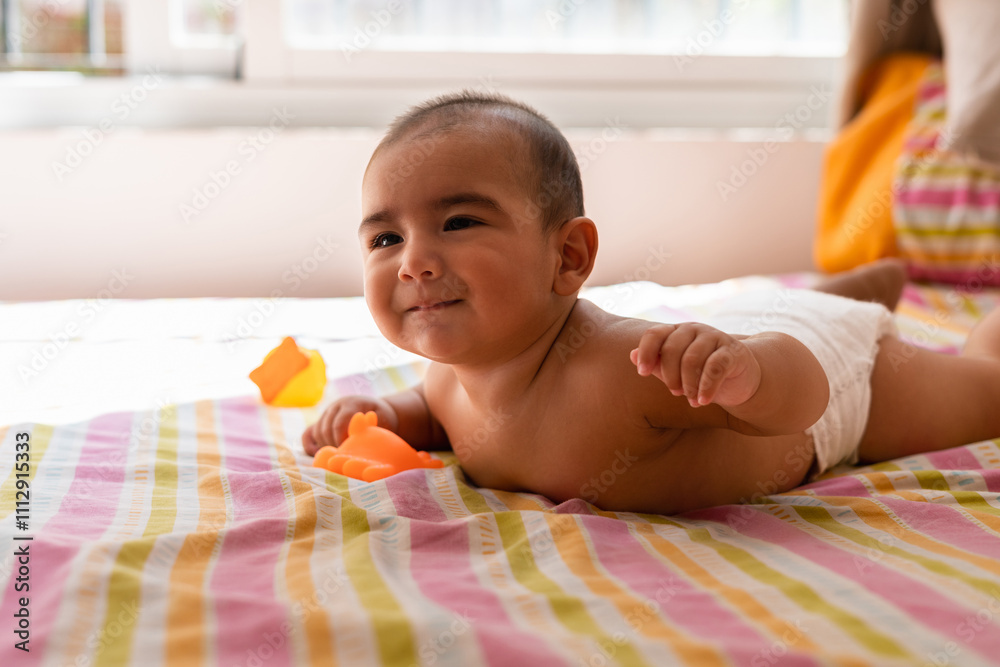 Baby smiling in bed while holding a toy Baby smiling in bed while holding a toy