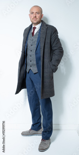 A modern corporate man in a tailored blue three piece suit. Grey tweed knit business suit for lawyers, bankers and for men with high power positions. Corporate barrister and peaky blinders cos play. photo