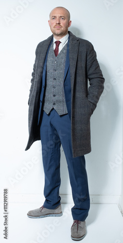 A modern corporate man in a tailored blue three piece suit. Grey tweed knit business suit for lawyers, bankers and for men with high power positions. Corporate barrister and peaky blinders cos play. photo