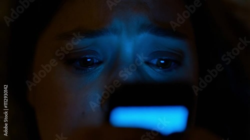 Sad Girl Crying in the Dark Lit by Phone Glow. Victim of Cyberbullying