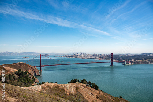 Golden Gate Bridge spanning San Francisco Bay, with the city skyline in the background under a clear blue sky.
