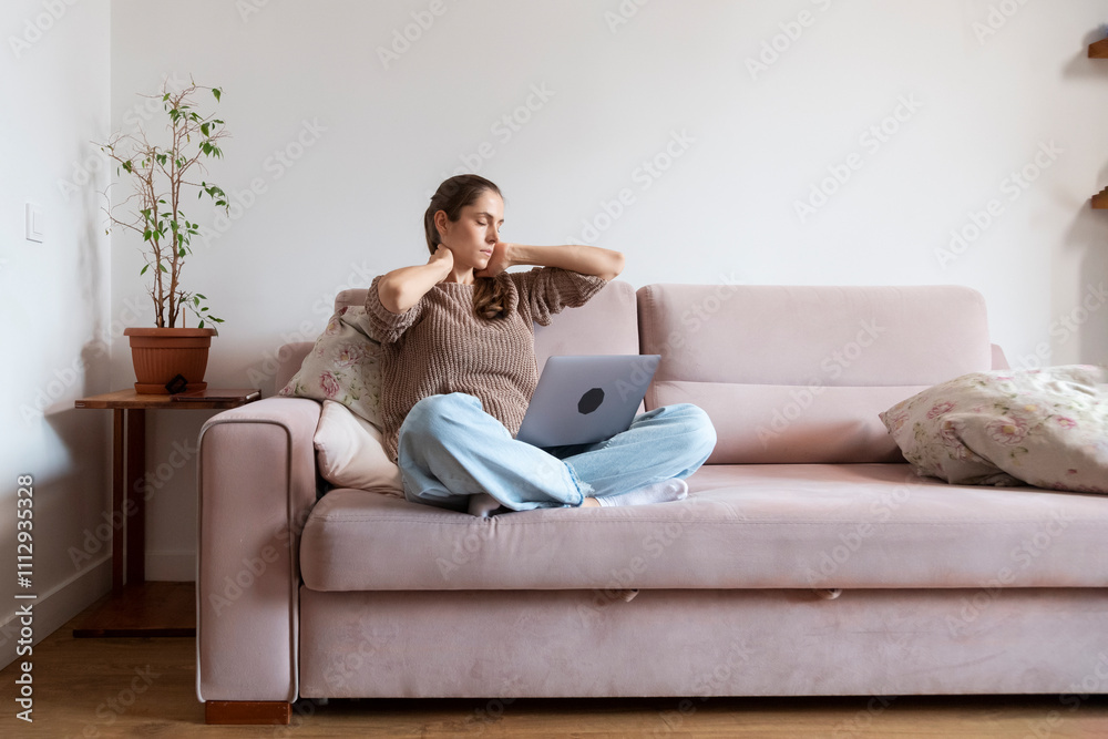 Tired woman suffering from neck pain while working on laptop at home Tired woman suffering from neck pain while working on laptop at home